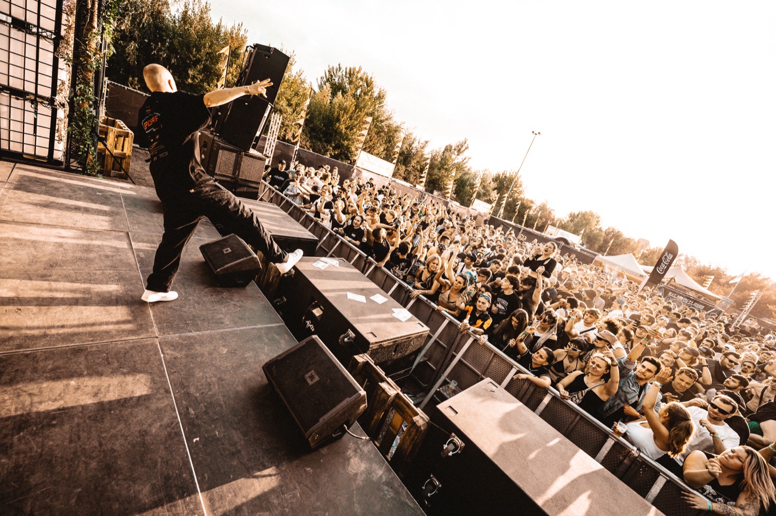 DJ throws hands to crowd, golden hour